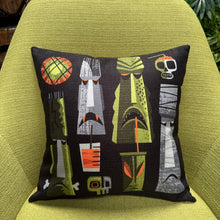 Colorful 'Monster Island' pillow cover featuring tiki motifs, set against a vibrant green chair.