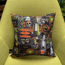 Colorful 'Monster Island' pillow cover featuring tiki motifs on a textured fabric, perfect for indoor decor.