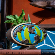 Handcrafted green ceramic Tiki mug shaped like a globe, featuring vibrant colors and tropical decor elements.